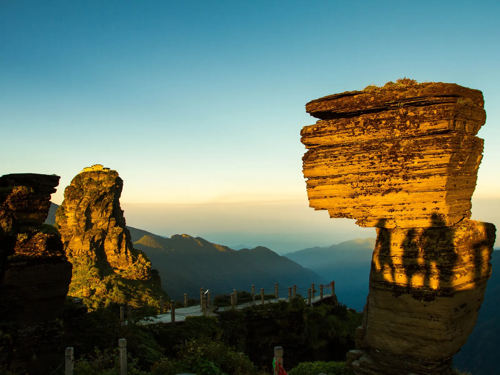 The Red Clouds Golden Summit of Fanjingshan: a split rock shaft glowing gold at sunset.