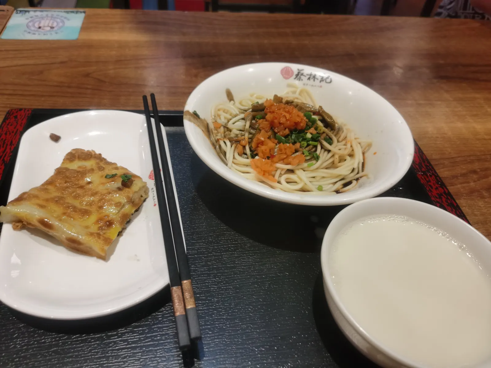A Wuhan breakfast set: sesame-paste hot dry noodles, a wedge of doupi and a bowl of soy milk.
