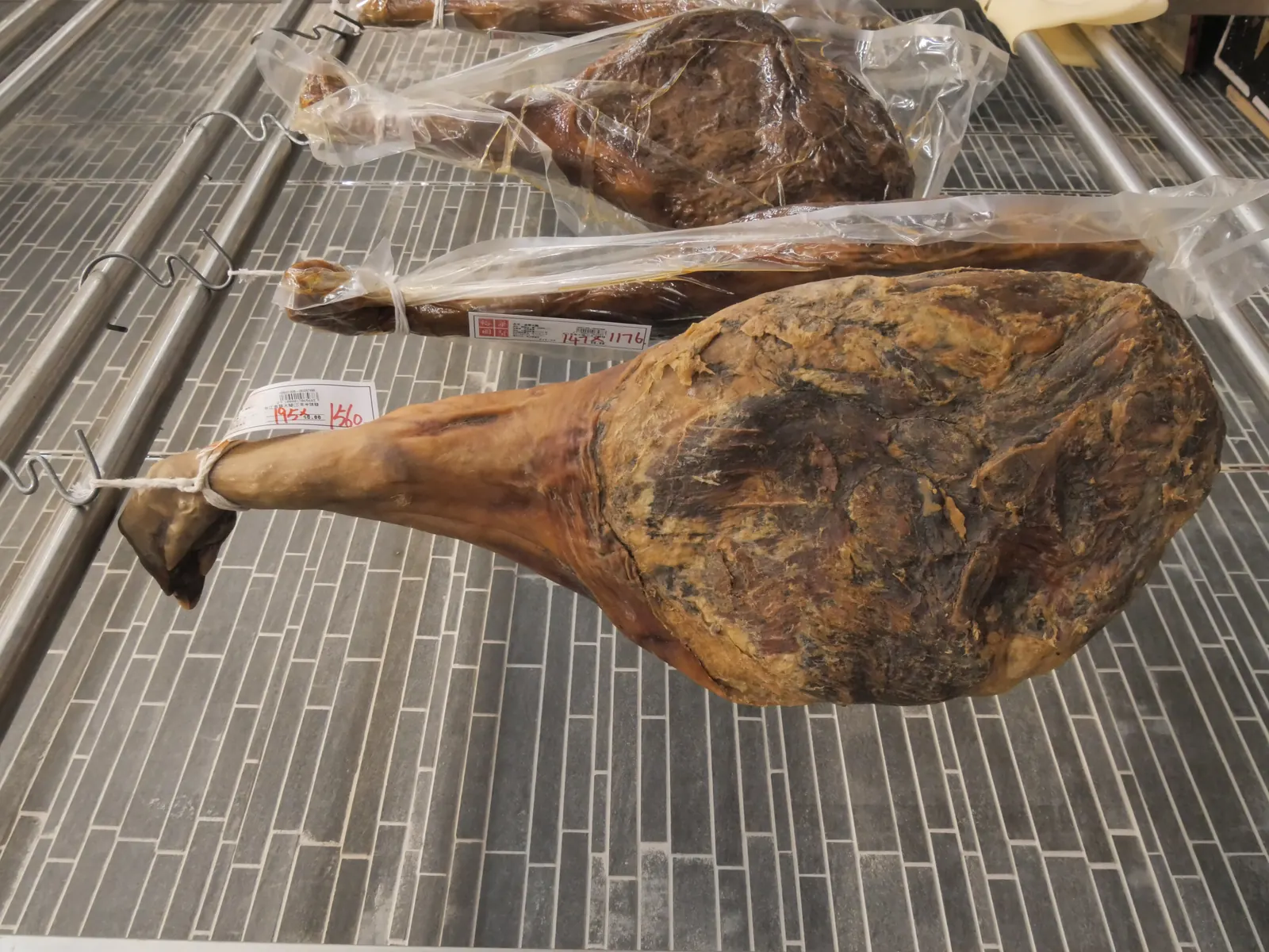 A whole Jinhua ham hanging on a shop rack, its cured surface dark and amber.