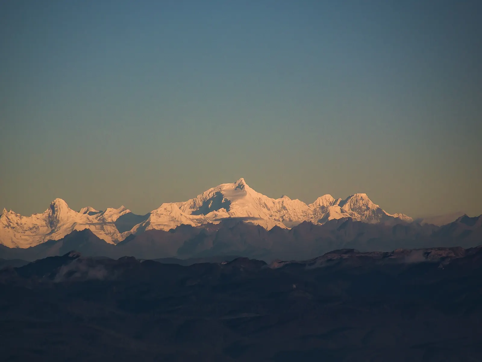 First dawn light turning the snow of Kawagarbo, highest peak of Meili, gold above a blue valley.