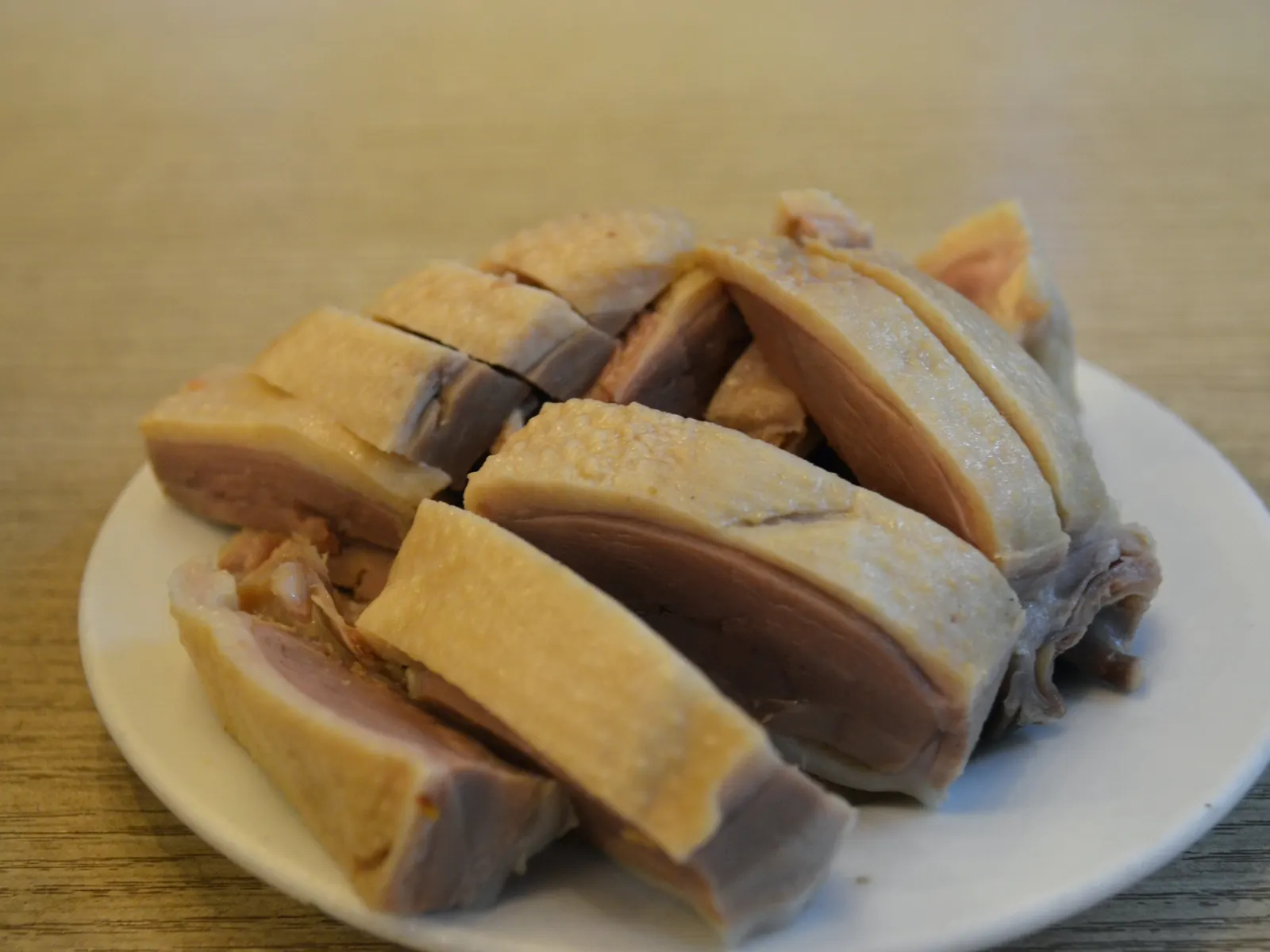 Chopped Nanjing salted duck served cool on a white plate, porcelain-white flesh under a thin amber skin.