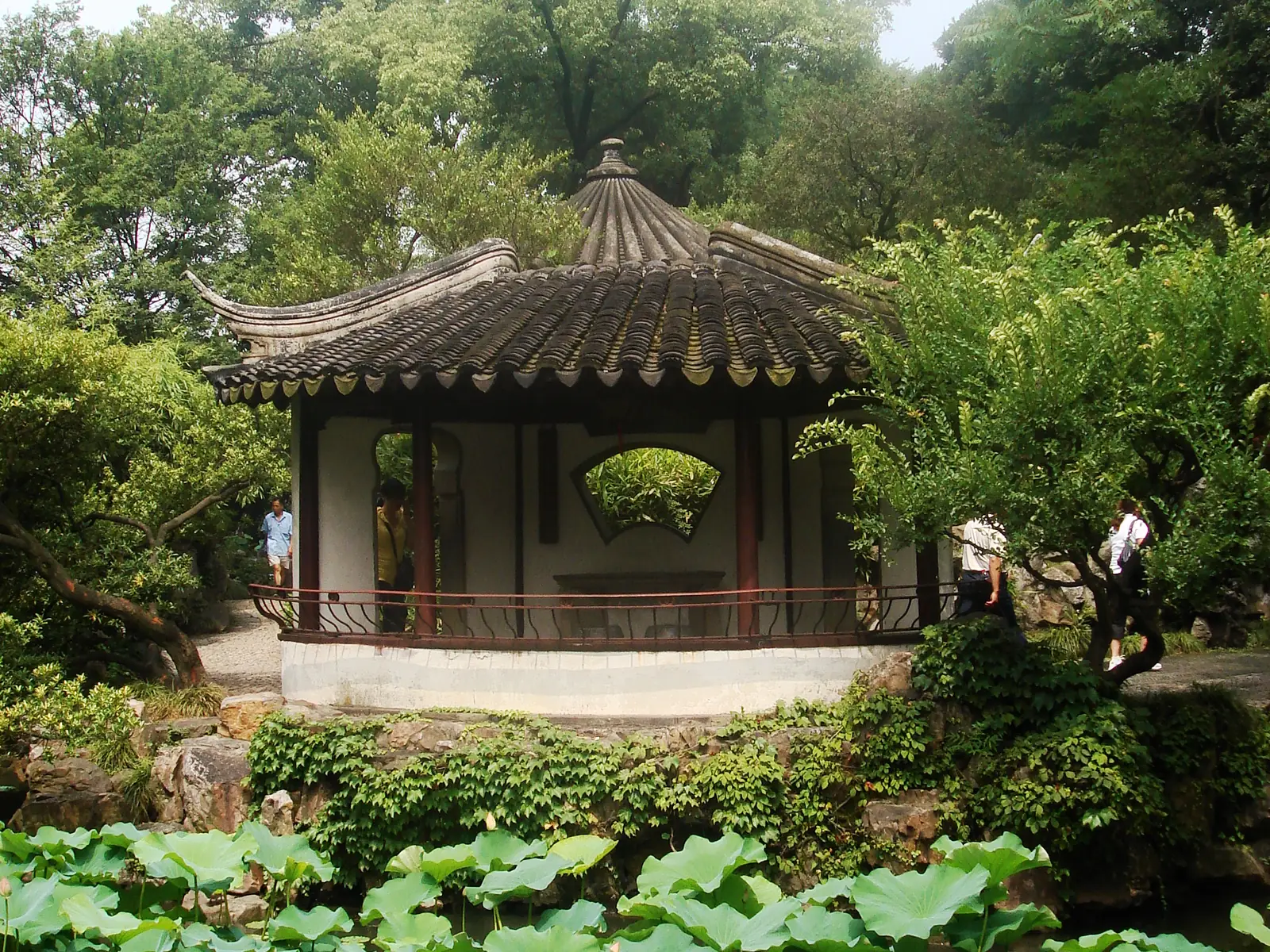 A hexagonal pavilion with upturned eaves and a fan-shaped window rises over the lotus pond of the Humble Administrator's Garden, Suzhou.