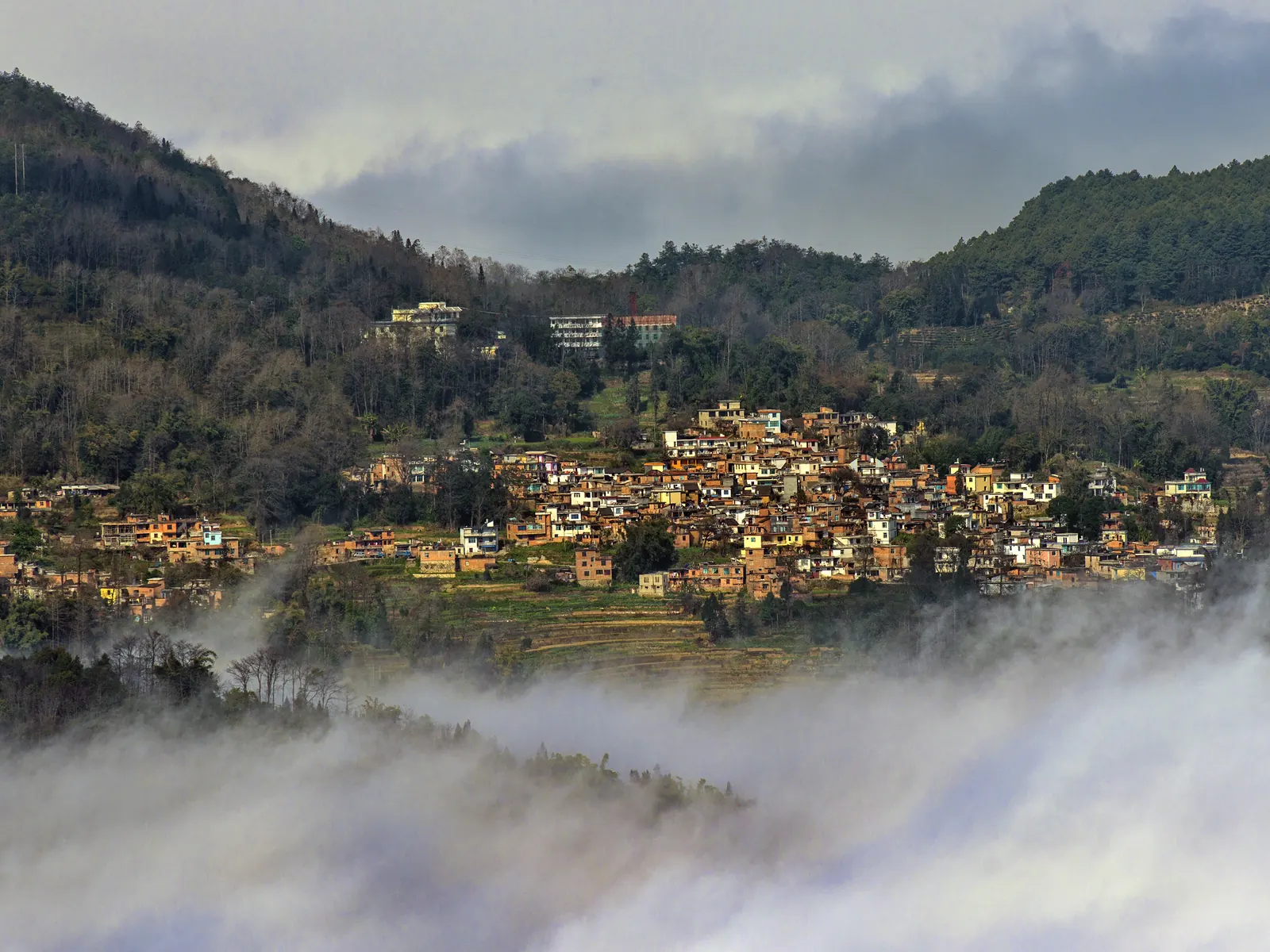 Cloud sea spilling through the Yuanyang rice terraces and village rooftops at dawn.