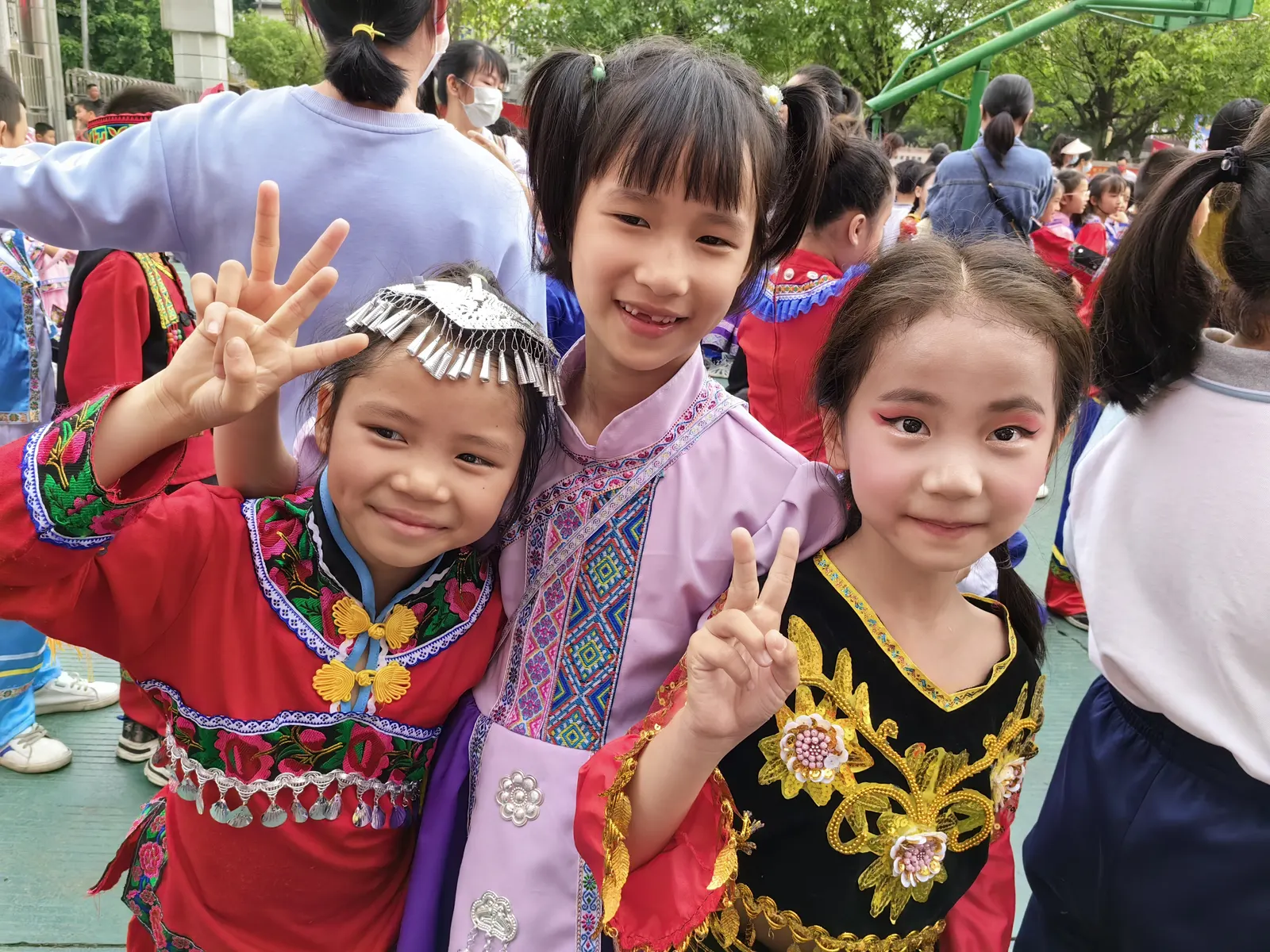 Zhuang girls in festival brocade jackets and silver headpieces at a Guangxi song-fair gathering.